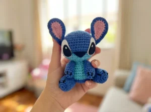 Free Stitch amigurumi pattern — finished blue alien plush with giant ears and felt eyes, sitting on a wooden surface