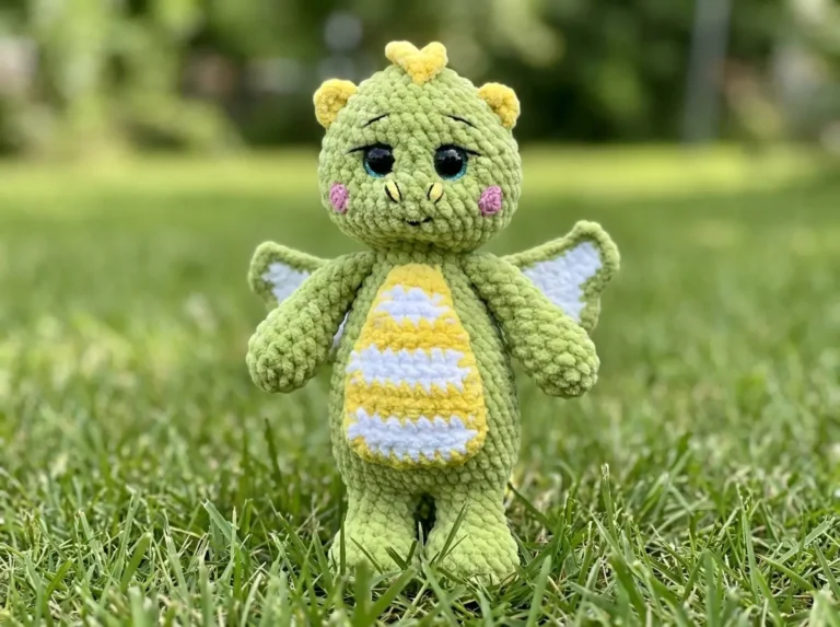 Side view of a green velvet dragon toy with yellow spikes on grass for this dragon crochet pattern free.
