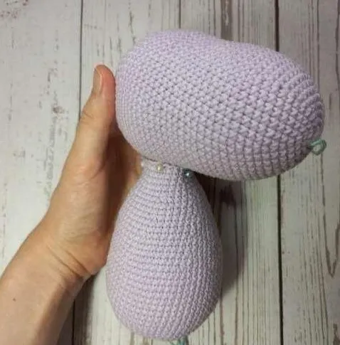 Crocheted light lilac unicorn head pinned securely to the top of the body piece for assembly.