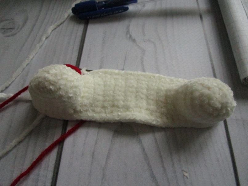 Top-down view of the amigurumi unicorn's white plush legs joined by a flat 17-row crocheted bridge piece.