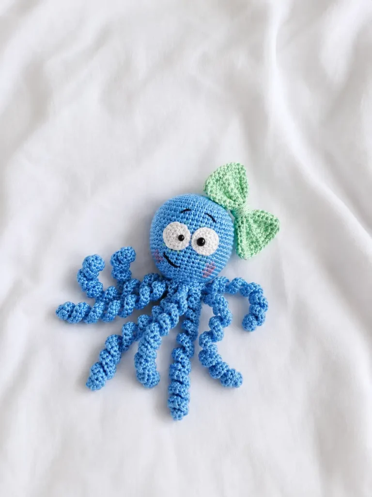 Free octopus amigurumi pattern finished in soft blue with a green bow and curled tentacles