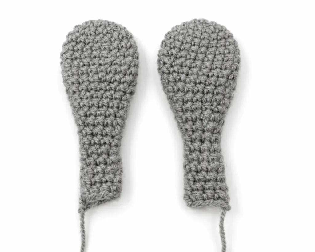 A pair of completed steel-gray crocheted ears for the bucktooth bunny amigurumi, flattened and placed side by side against a white background.