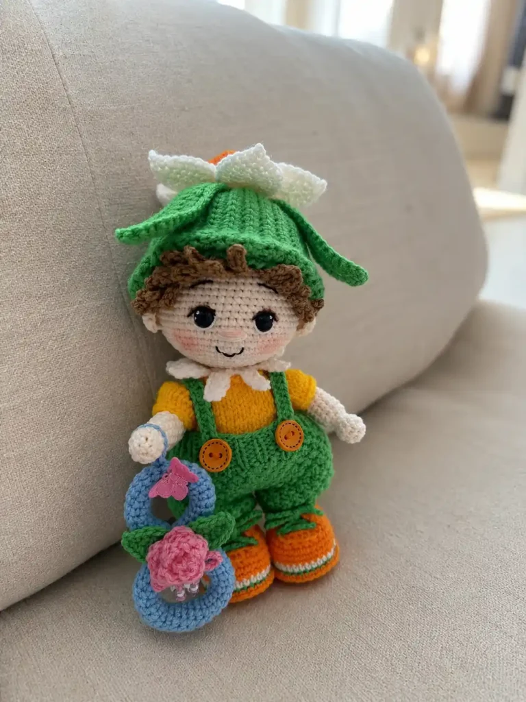 Handmade narcissus flower doll amigurumi named Jonquil wearing a green ribbed hat with a blooming white and yellow narcissus, a yellow jacket, green overalls, and holding a blue crocheted number eight.