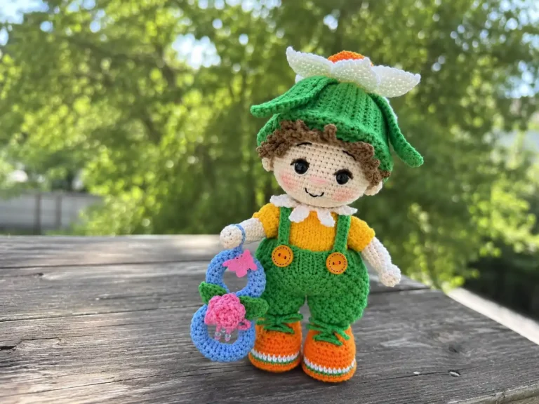 Crochet narcissus flower doll amigurumi free pattern on wooden table with green yarn overalls and leaf hat.