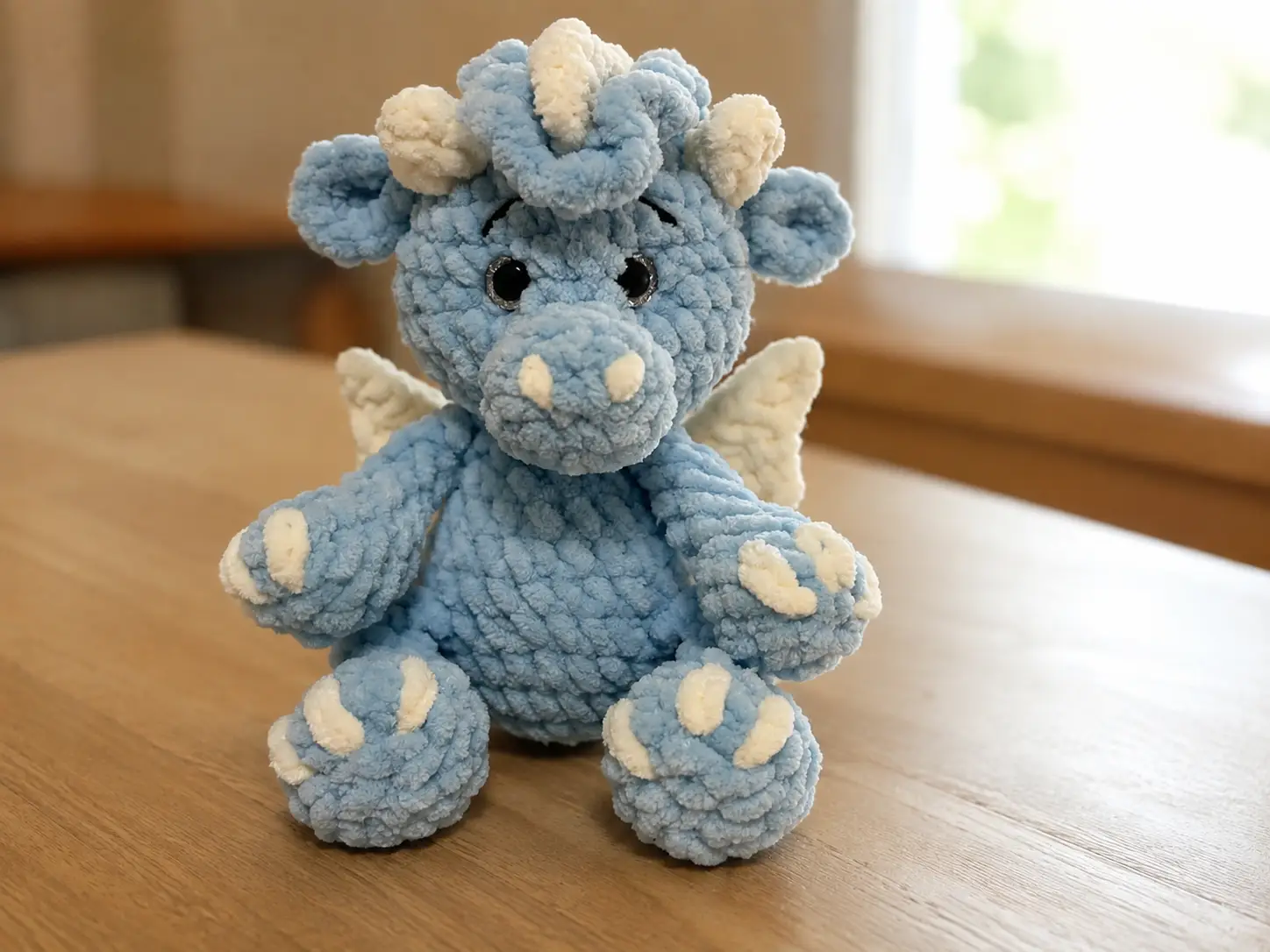Collage of a blue crochet baby dragon amigurumi indoors, in a woven basket, and sitting on a beige couch.