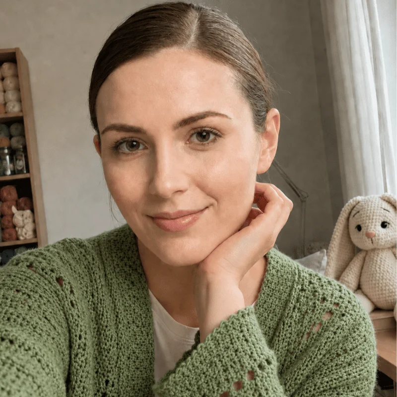 Emma, founder of AmiLoops, in her crochet workspace with a handmade amigurumi bunny in the background.