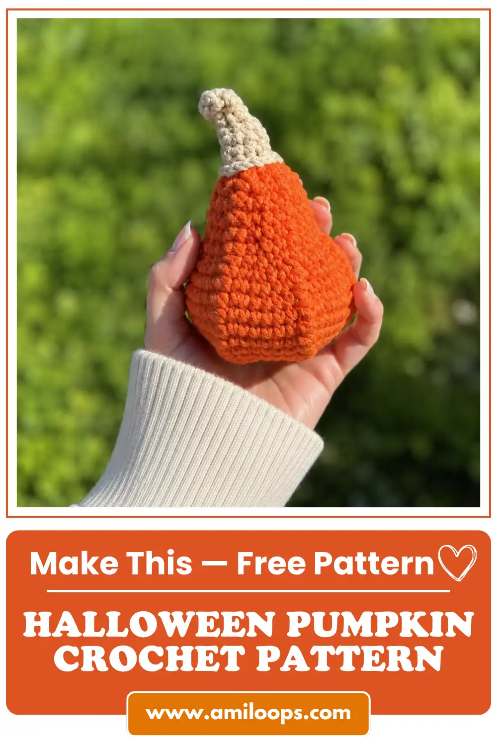 A single hand wearing a white ribbed sweater holds an orange crocheted gourd from the halloween pumpkin crochet pattern.