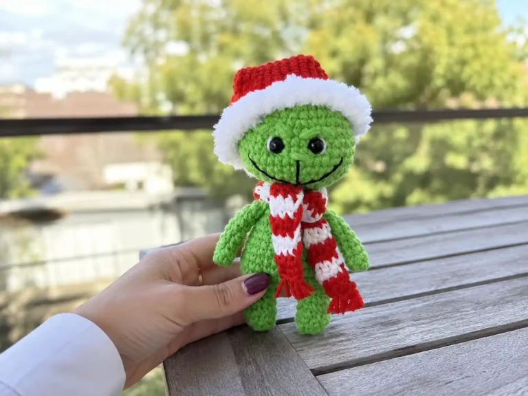 Collage of a small green crochet Grinch amigurumi wearing a red and white Santa hat, shown held in hand and on a couch.