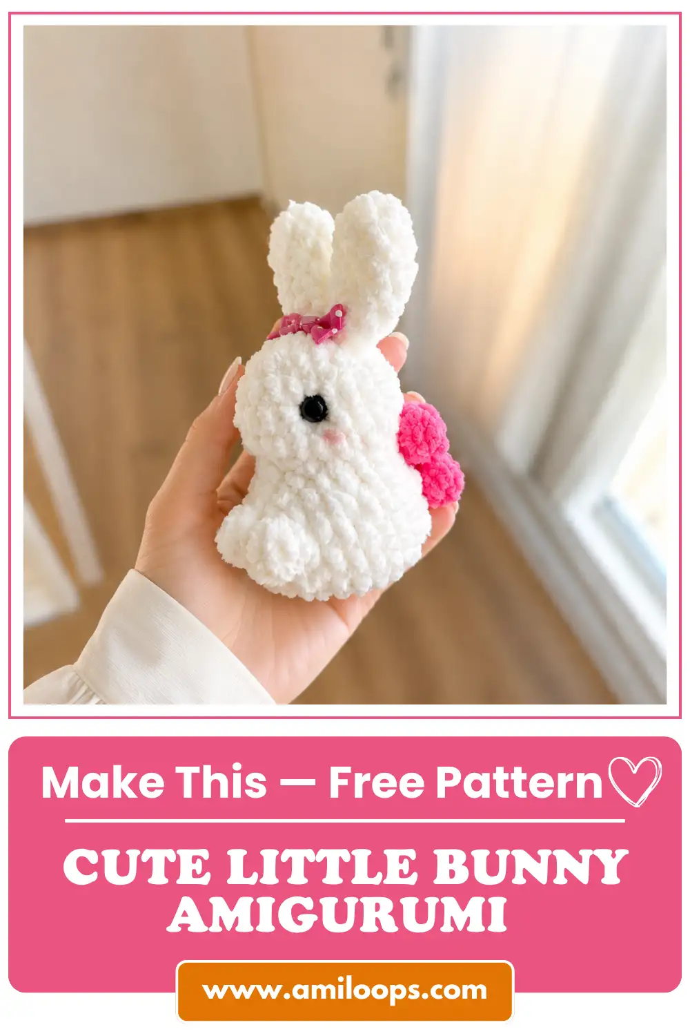 Hand holding a white plush little bunny amigurumi free pattern featuring a pink bow and tail indoors near a window.