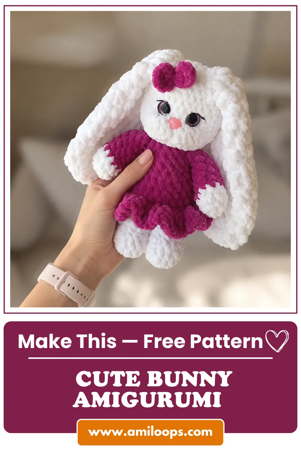 A hand holds a white mini bunny amigurumi free pattern wearing a magenta dress made of thick velvet yarn, soft background.