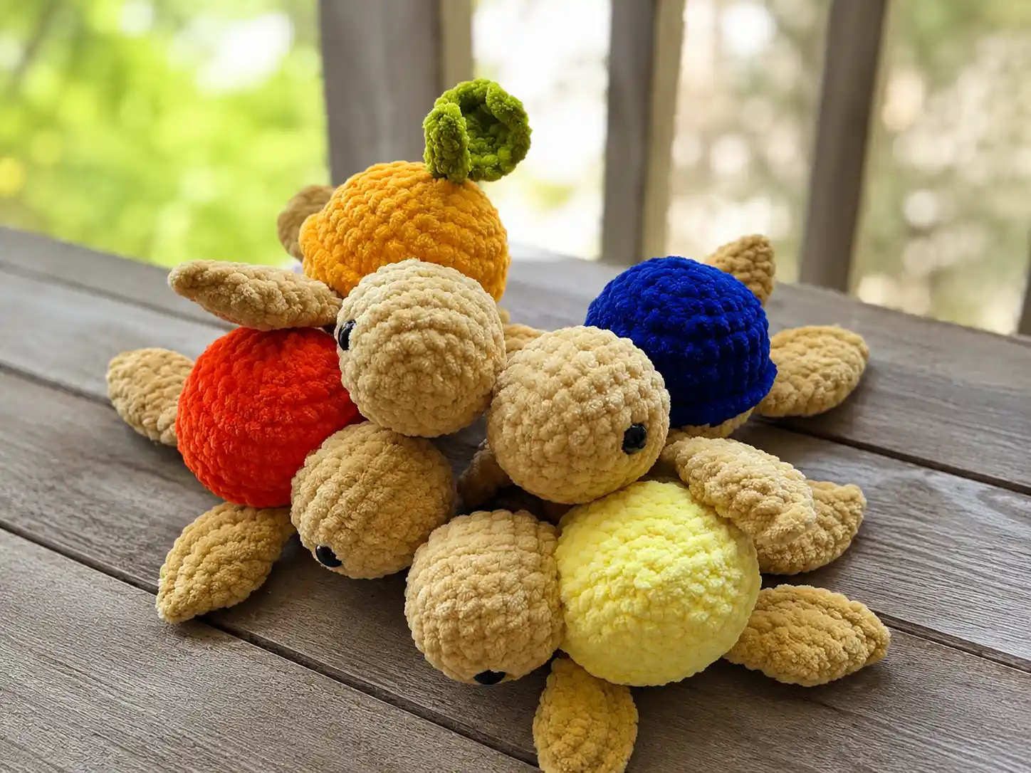 An orange and tan crochet mini turtle amigurumi with a green leaf topper, held in a hand.