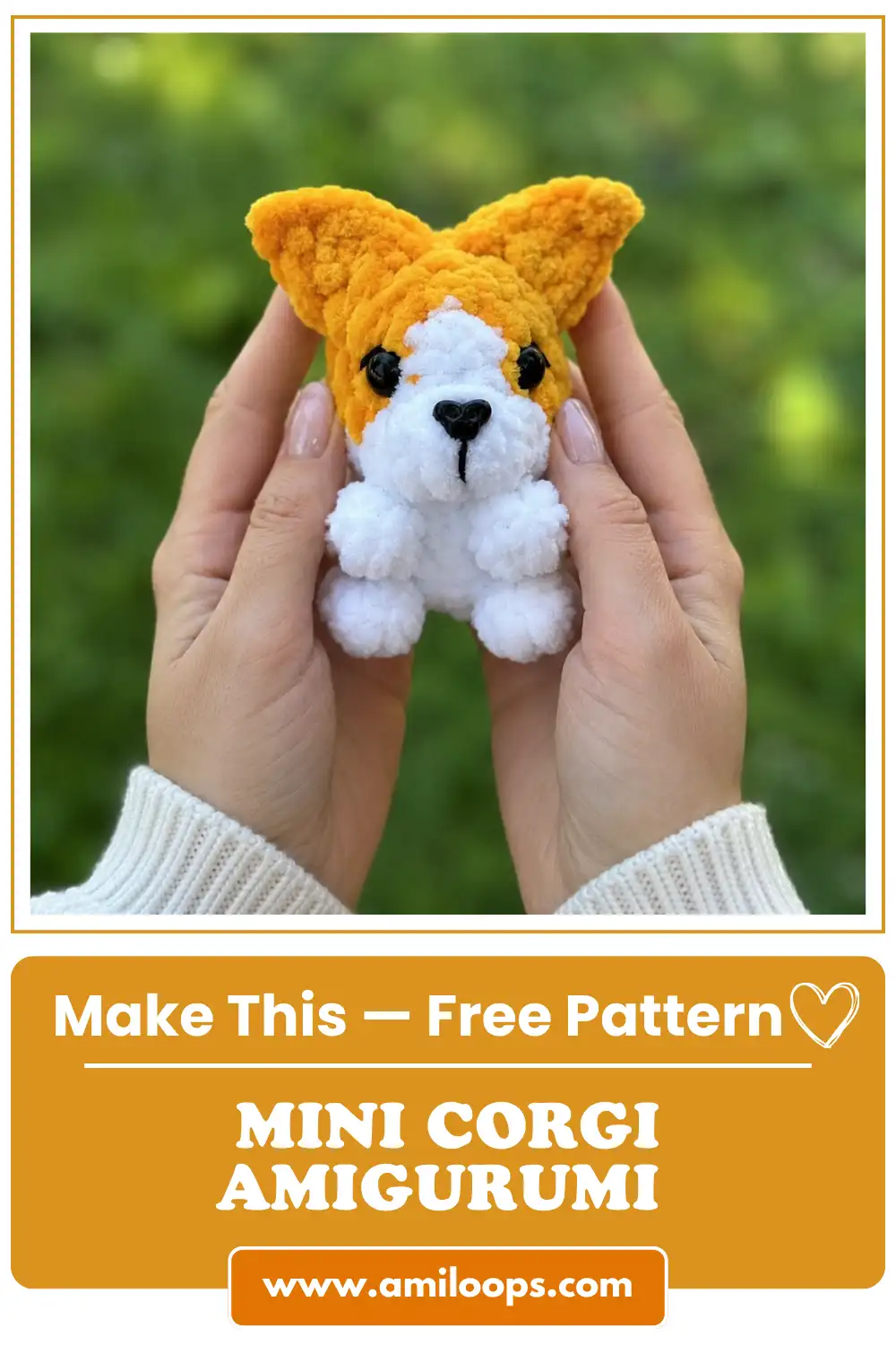 Two hands hold a fluffy orange and white yarn dog against a green background from this mini corgi amigurumi free pattern.