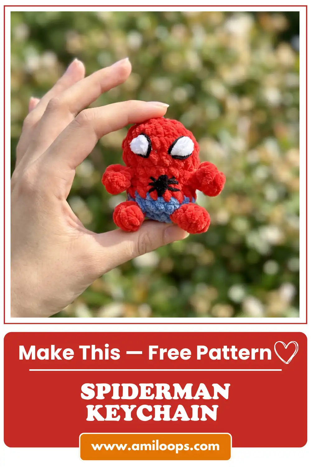 Hand holding a red and blue plush yarn toy from the spiderman amigurumi keychain free pattern against blurred green bokeh.