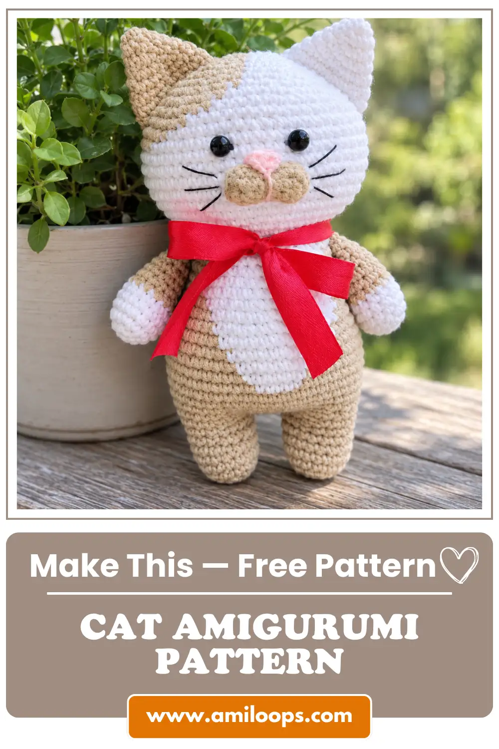 Beige and white Barsik the cat amigurumi pattern with a red ribbon standing on a wooden table next to a potted plant.