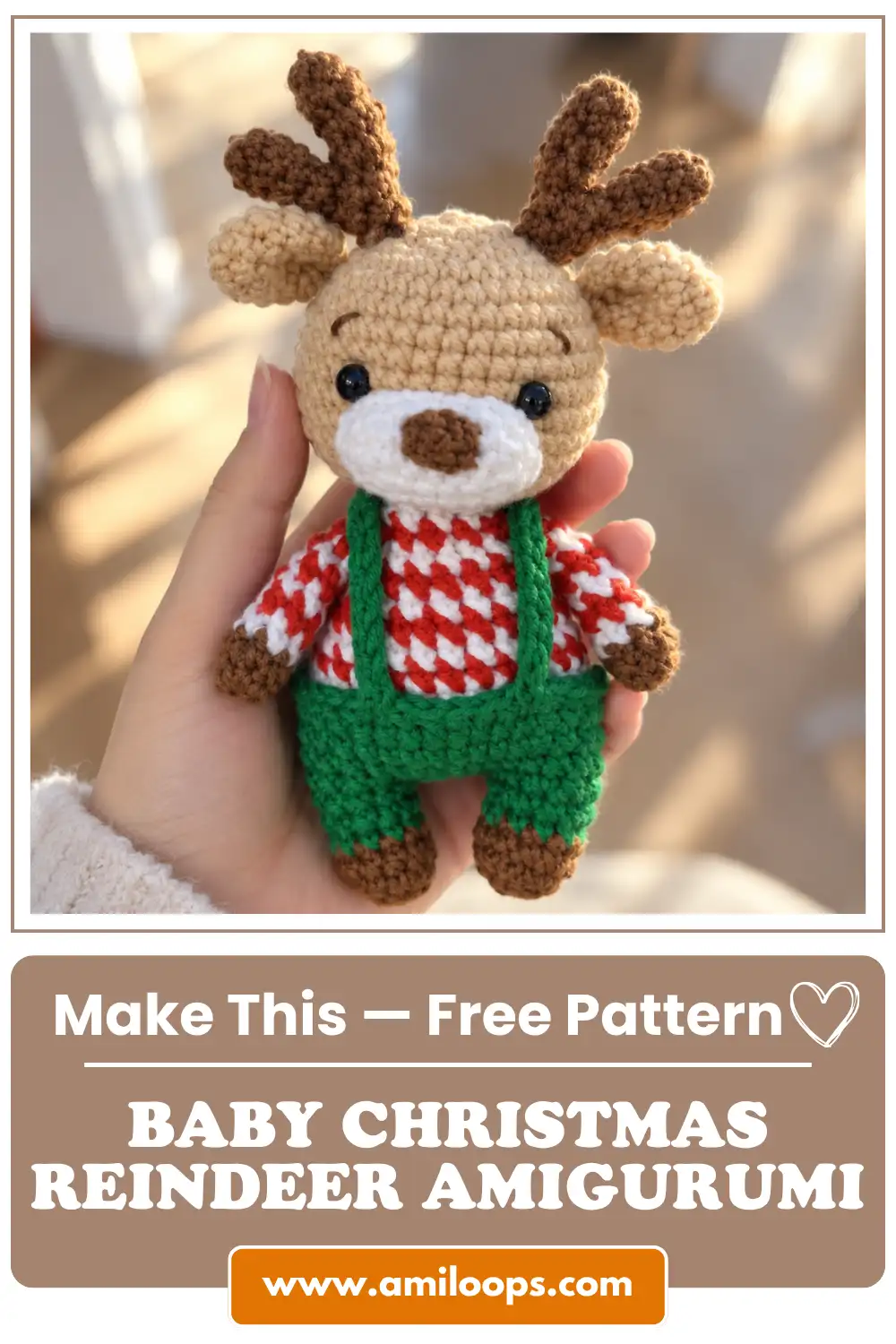A hand holding a cute crochet Christmas reindeer amigurumi toy wearing a red-and-white sweater and green overalls against a bright, softly blurred indoor background.