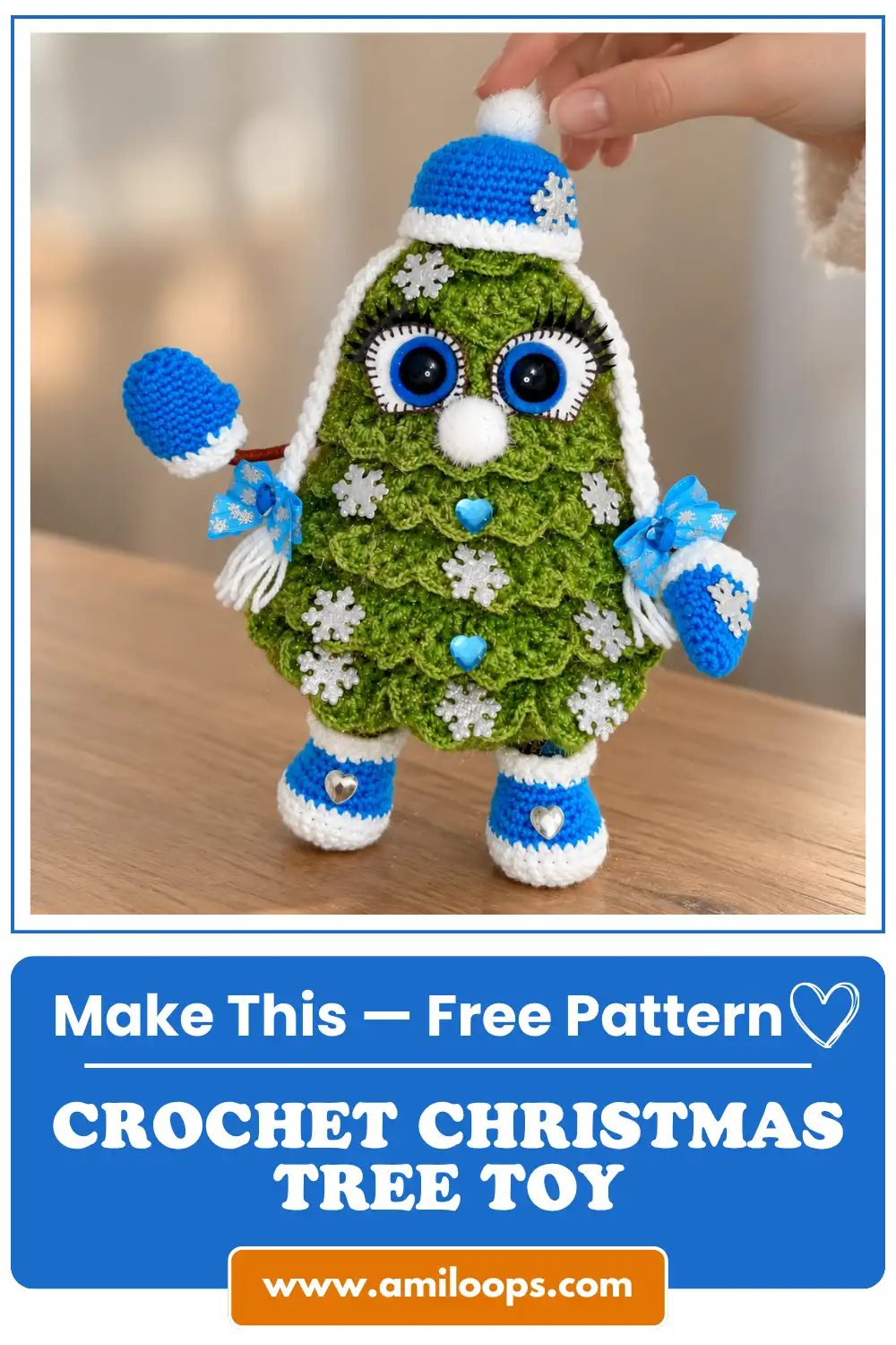 Hand holding a green crochet Christmas tree toy with blue boots, mittens, and hat on a wooden table.