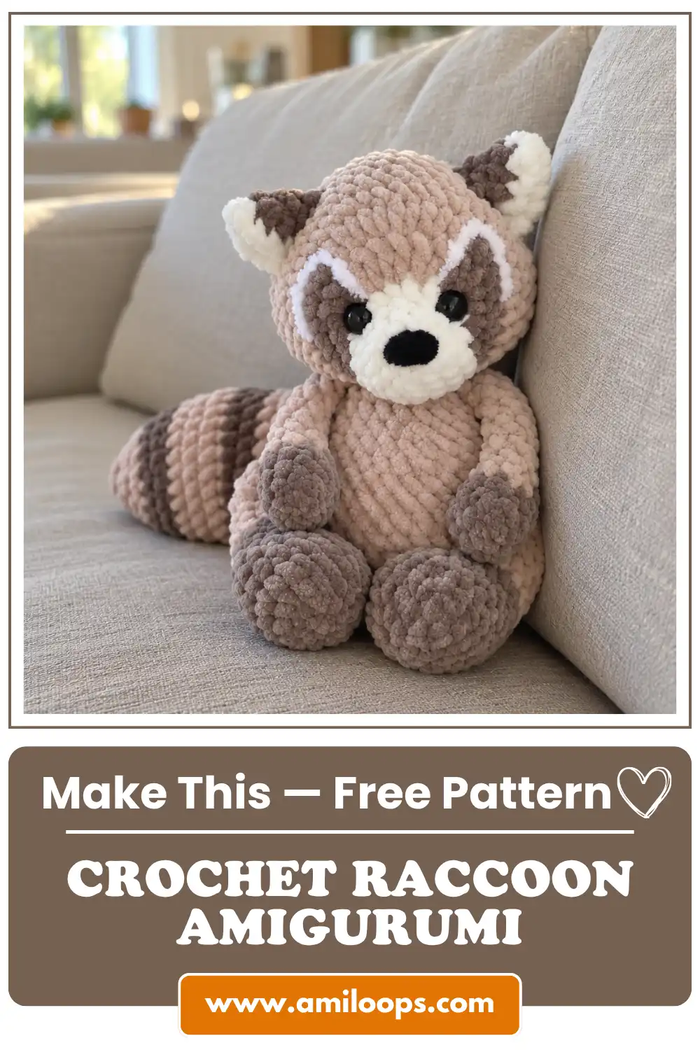 A fluffy beige and brown crochet raccoon amigurumi pattern sitting upright on a light gray sofa in a bright sunny room.