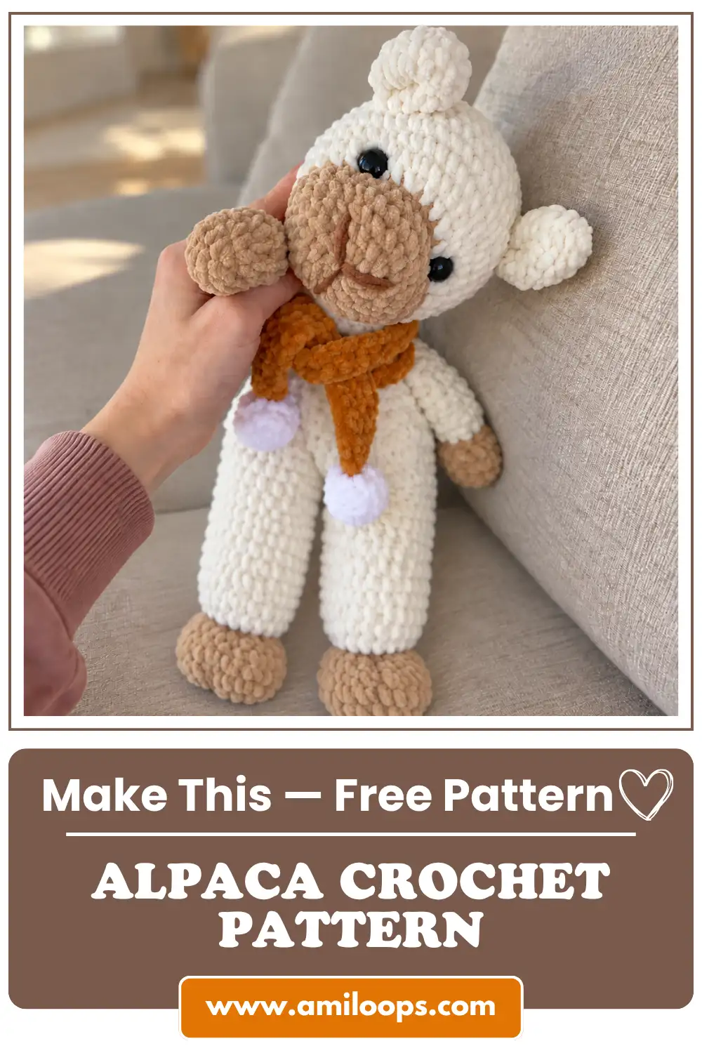 Hand touching a soft white and brown alpaca crochet pattern amigurumi with an orange scarf on a beige sofa.