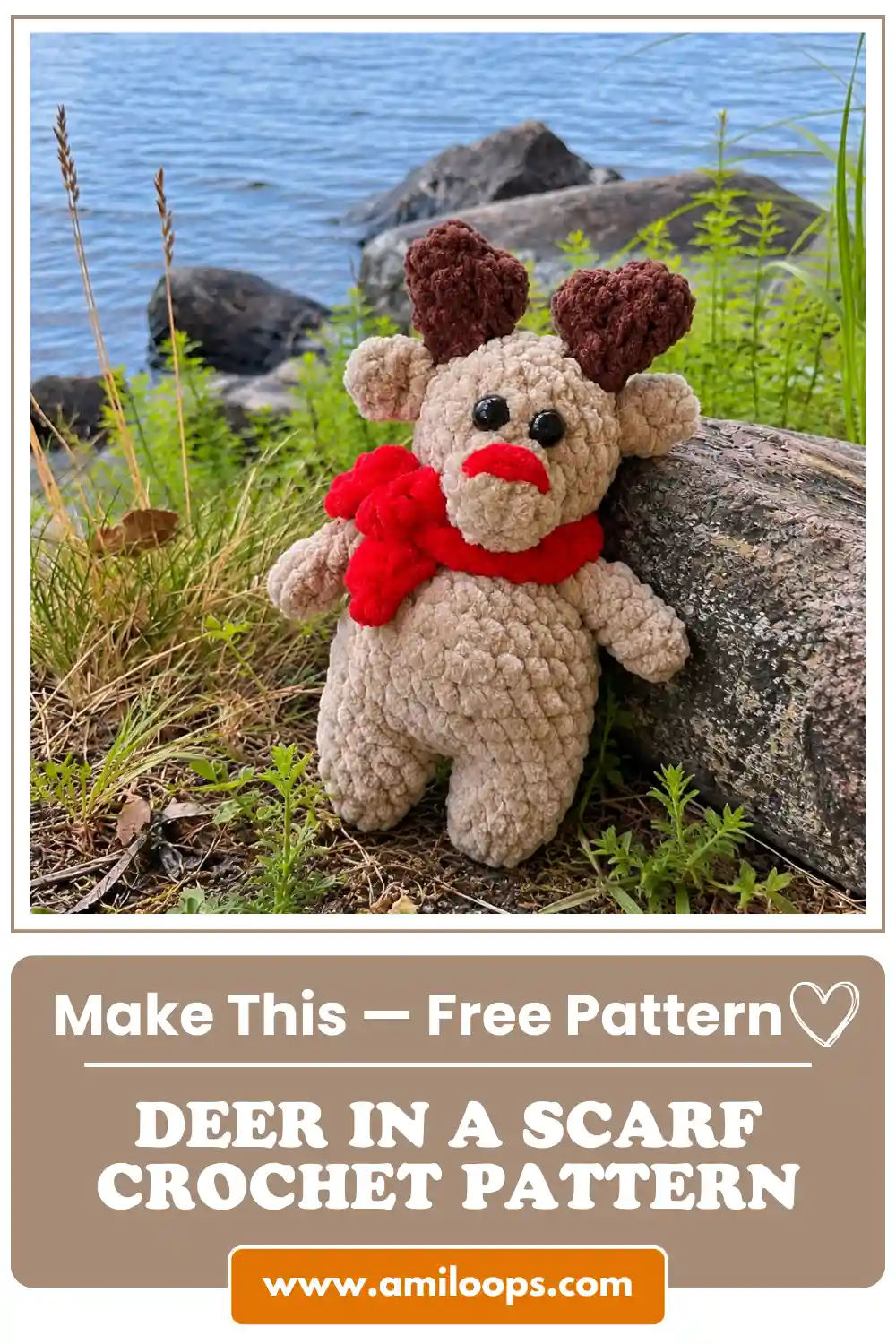 Beige chenille toy from a deer in a scarf crochet pattern sitting by a log with a blue lake background and red yarn scarf.