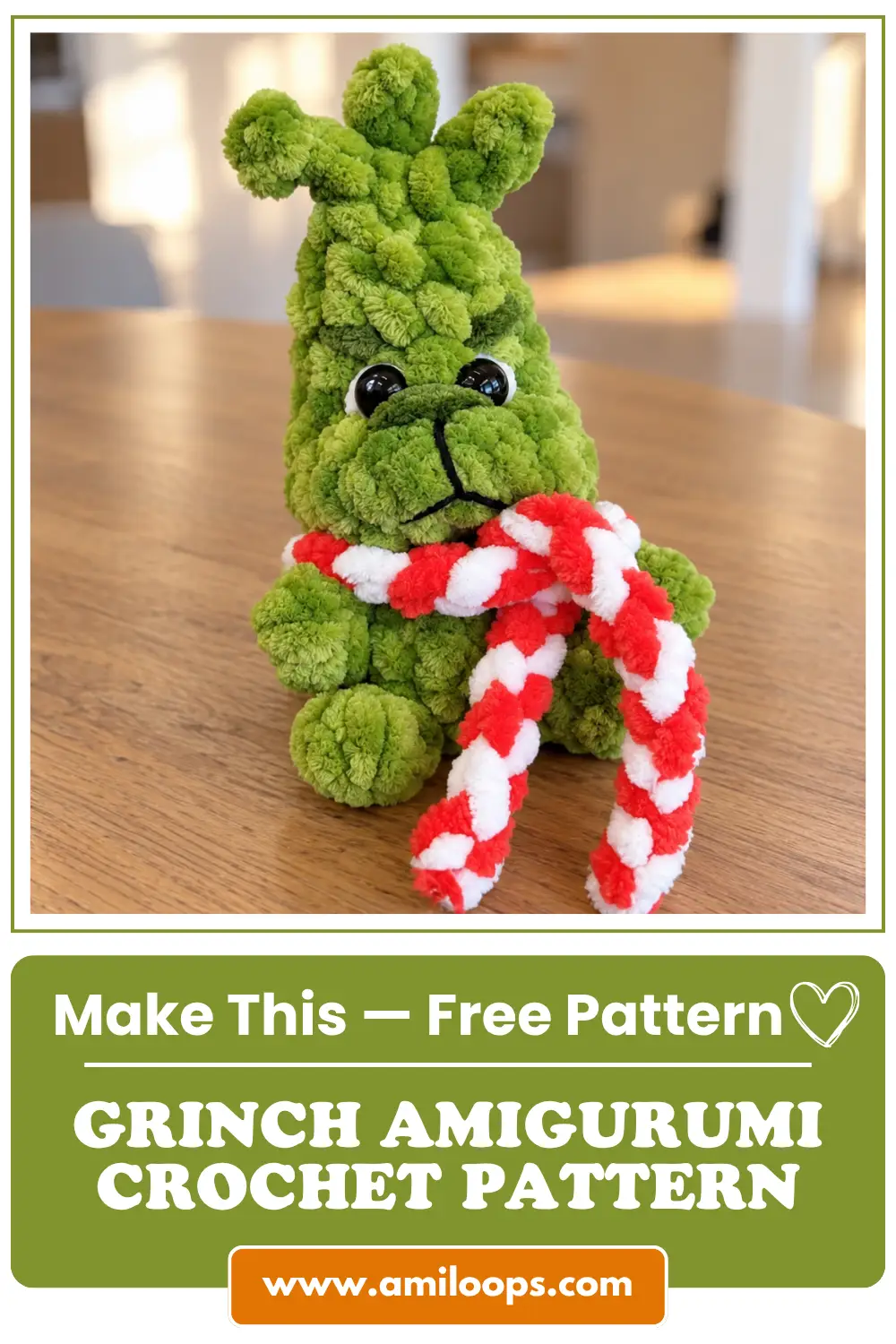 A fluffy green grinch amigurumi crochet pattern toy with a red and white scarf sitting on a wooden table.