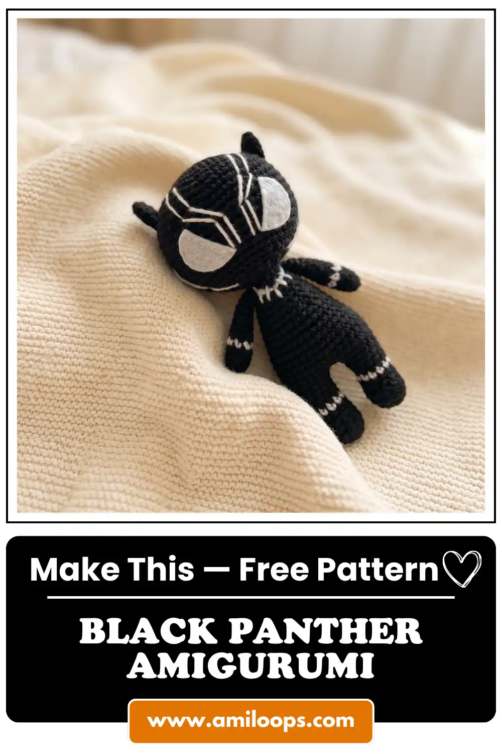 Black yarn black panther amigurumi with white mask embroidery resting on a textured cream knit blanket.