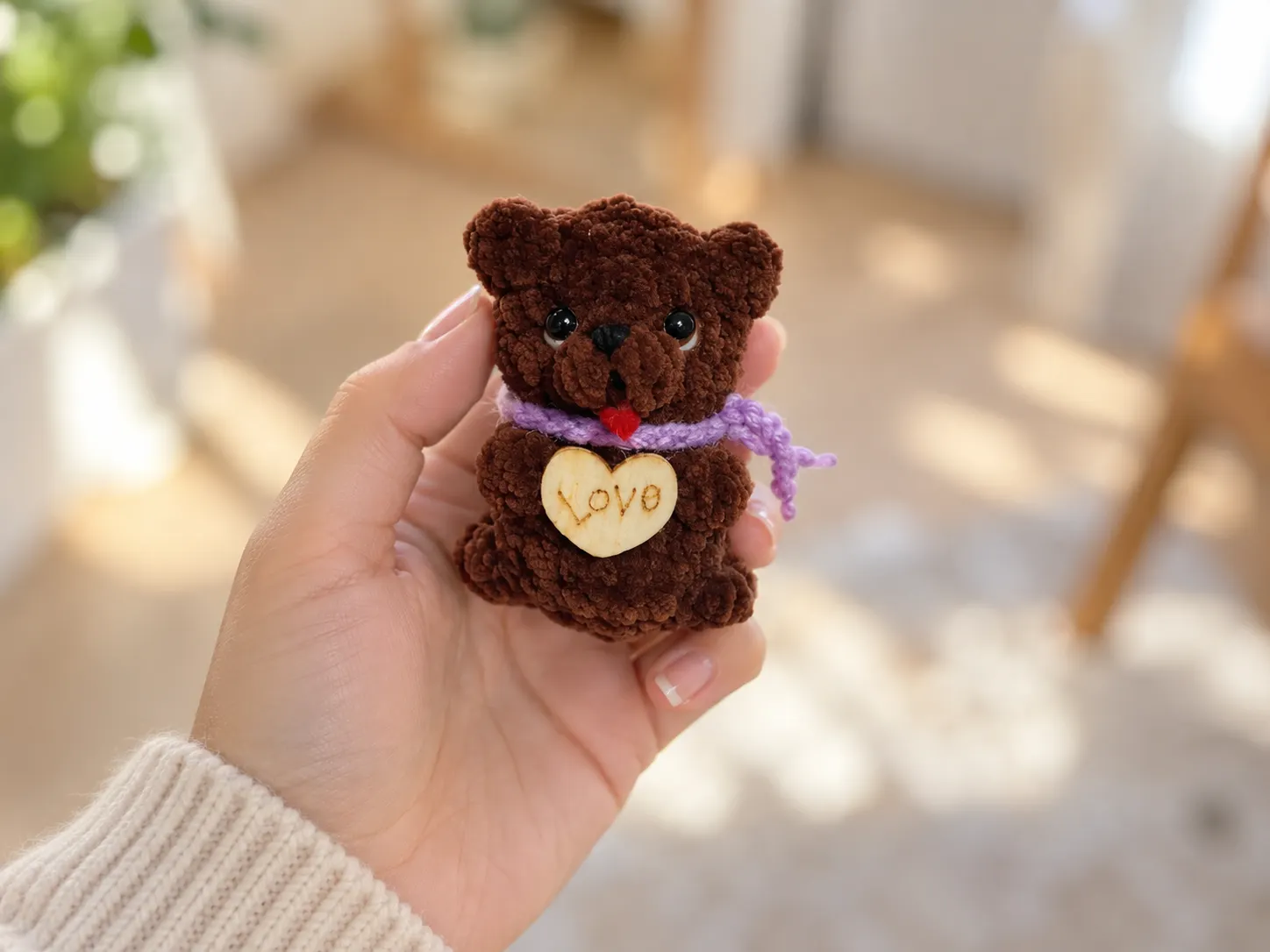 A hand holding a tiny brown crochet bear with a purple scarf and heart charm; more photos show it on a couch and table.