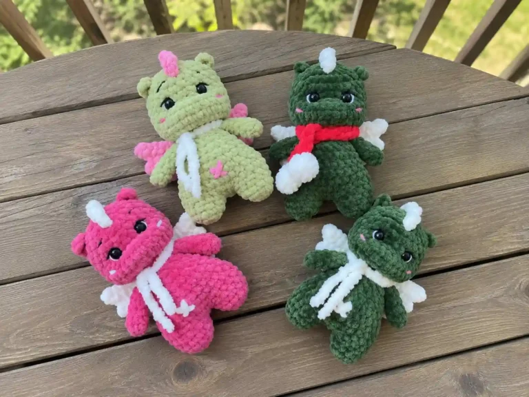 Free mini dragon amigurumi pattern worked entirely in plush super bulky yarn for a squishy, rounded silhouette. Spiked wings, a curled tail, and a hand-sculpted face give this dragon real personality. Save this piFour crochet mini dragon amigurumi in green, pink, and olive yarn colors with wings and horns, displayed together. and grab your hook!