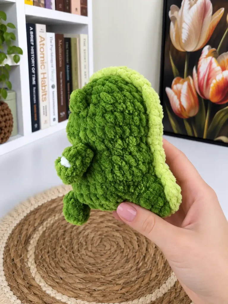 Side profile view of the green plush mini dragon crochet pattern showing the light green crest running down the back.