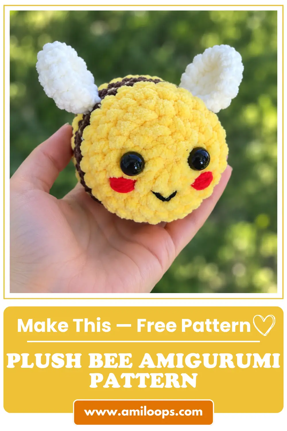 Close-up of a smiling fuzzy plush bee amigurumi with black eyes, red blush, and white wings held in an open hand outdoors.