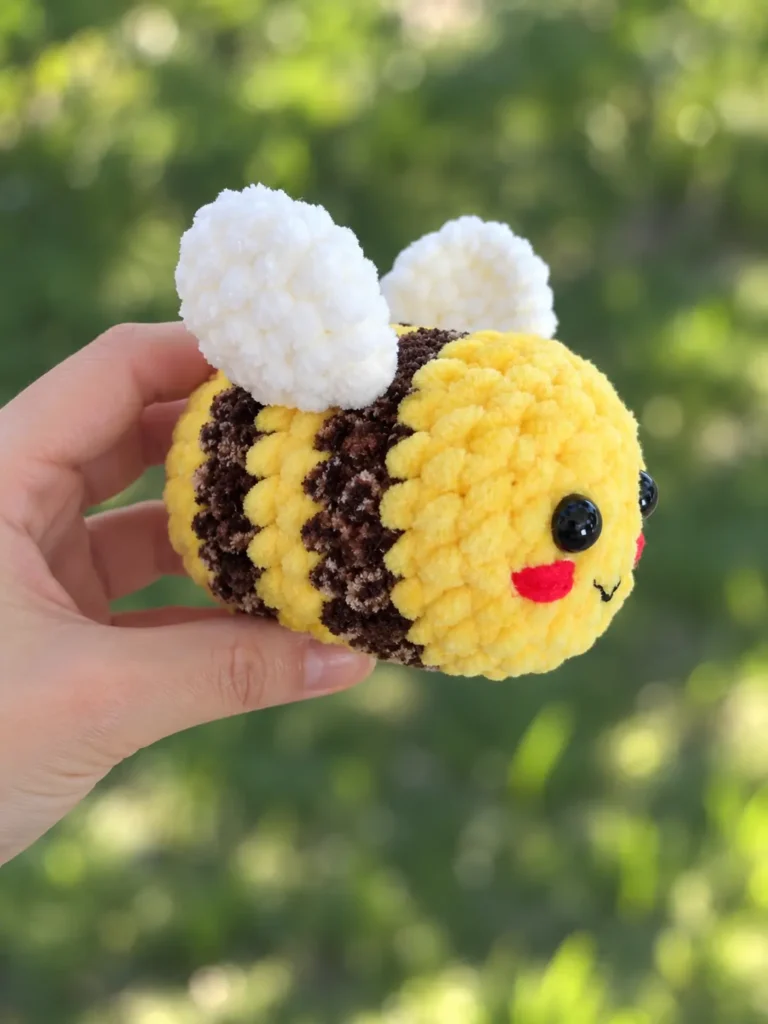Side profile of the plush bee amigurumi held in hand, showing yellow body segments and dark brown stripes.